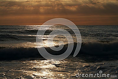 Panoramic view of the sea surface at sunset. Surf waves glisten in the sunlight. Picturesque natural background. Stock Photo