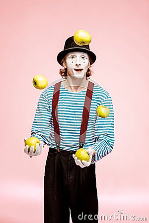 Pantomime juggling with apples on the pink background Stock Photo