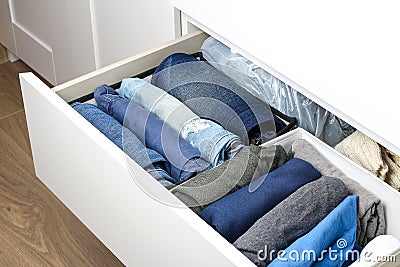Pants folded according to the method of Marie Kondo. Vertical storage of clothes in a chest of drawers. Storage organization. Stock Photo