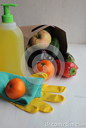 A paper bag is on with vegetables and fruit, a bottle of disinfectant, gloves and rags. Stock Photo