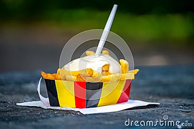 Paper box in colors of Belgian flag with fried potato frit chips and mayonnaise sauÑe Stock Photo