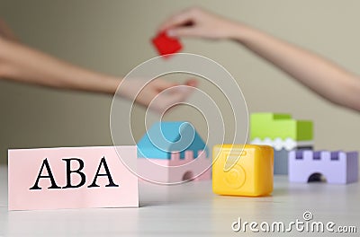 Paper card with abbreviation ABA Applied behavior analysis and blocks on white table, space for text Stock Photo