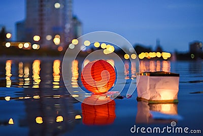 Paper Chinese lanterns floating in river with city lights reflections Stock Photo