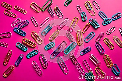 Paper clips of various colors on pink colored paper Stock Photo