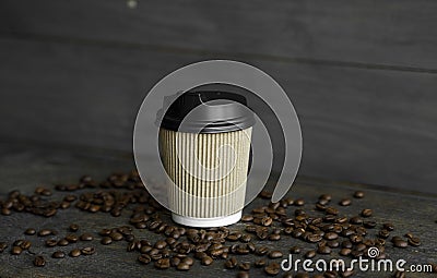 Paper cup of coffee with roasted coffee beans on wooden table background. Mug of black coffee. Stock Photo