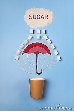 A paper cup is covered with a sugar rain umbrella on a blue background. The concept of reducing or giving up sugar. Tea or coffee Stock Photo