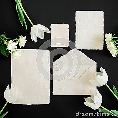 Paper envelop, white cards and flowers on black background. Flat lay, top view. Creative valentines day concept Stock Photo