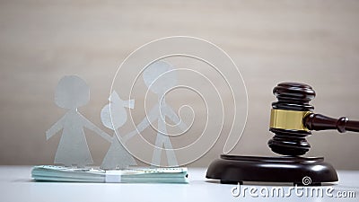 Paper family and dollars table, gavel standing on sound block, divorce alimony Stock Photo
