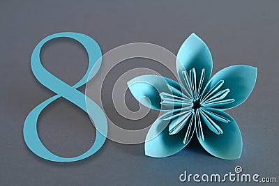 Paper flower from origami with the number eight on a gray background. March 8, International Women`s Day. Stock Photo