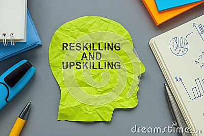 A paper head with inscription Reskilling and upskilling. Stock Photo