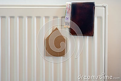 Paper house and wallet with money on the radiator. Stock Photo