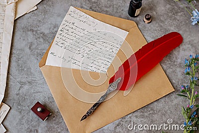 Paper letters, craft carpet, quill, inkwell and flowers lie on the table. Bright sunny day. View from above. Stock Photo