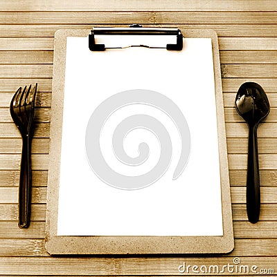 Paper menu with black plastic fork and spoon juxtapose on a wooden table have space, vintage style Stock Photo