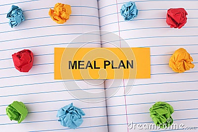 A paper note with the words Meal Plan on notebook sheet with some colorful crumpled paper balls around it Stock Photo