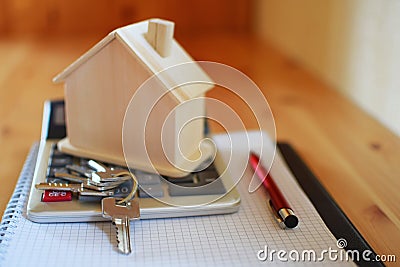 Paper notebook with calculator, house model, keys and pen on wooden table. Stock Photo