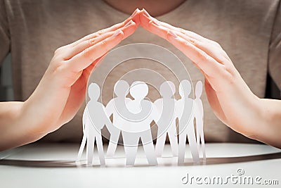 Paper people under hands in gesture of protection Stock Photo