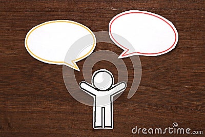 Paper person with colorful blank dialog speech bubbles on brown wood. Communication concept. Stock Photo