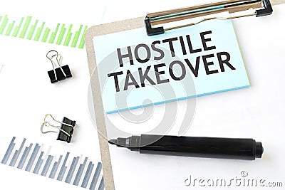 Paper plate, marker, diagram, chart and office tools. Text HOSTILE TAKEOVER Stock Photo