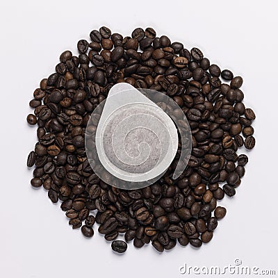 Coffee paper pod dosette for espresso laying on fresh ground coffee beans. on white background Stock Photo