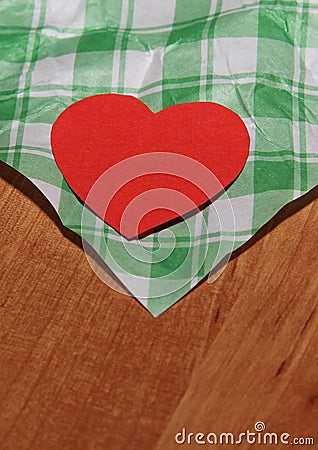 A paper red heart lies on a wooden surface on a white-green checkered surface Stock Photo
