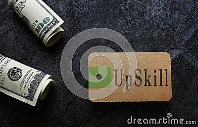 Paper tag with UpSkill text and hundred dollar bills Stock Photo