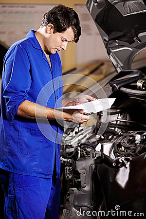 Paperwork, man and mechanic reading at engine of car, repair and maintenance. Checklist, technician and serious person Stock Photo
