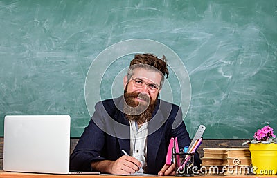 Paperwork part of teachers life. School teacher checking homework or test. Teacher sit desk with laptop. Check homework Stock Photo