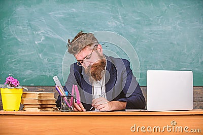 Paperwork part of teachers life. Teacher bearded hipster with eyeglasses sit in classroom chalkboard background. School Stock Photo