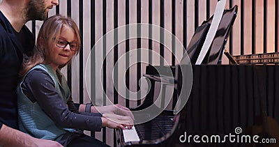 Papà che insegna pianoforte alle figlie che imparano il pianoforte a casa al pianoforte a casa. educazione infantile stock footage Papà che insegna pianoforte alle figlie che imparano il pianoforte a casa al pianoforte a casa. educazione infantile stock footage