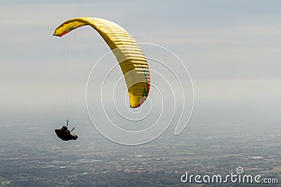 A para-glider up in the sky during a fly, with the campaign below him as background Stock Photo