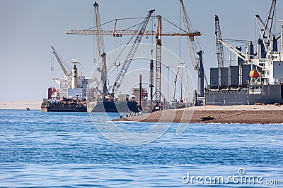 Paracas, Peru - 2019-12-05. In the port, cargo cranes are loading onto a cargo ship. Birds can be seen on the berug Editorial Stock Photo