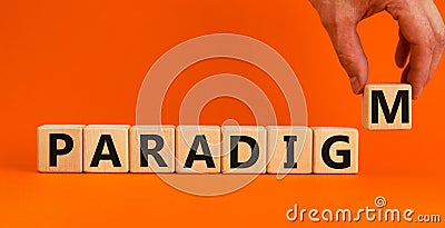 Paradigm word. Concept word `paradigm` on wooden cubes on a beautiful orange background. Male hand. Business and paradigm concep Stock Photo