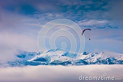 Paraglide over snow-capped peaks Stock Photo