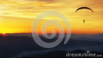 Paraglide silhouette over mountains at sunset Stock Photo