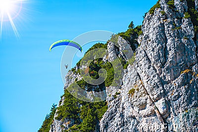 Paraglider flying dangerously close to a mountain peaks on a sunny autumn day Stock Photo