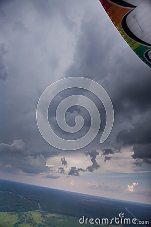 Paraglider under the thunderclouds, the multi-colored wing is visible Stock Photo