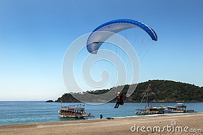 A paragliding comes in to land on Oludeniz Beach on the Turquoise Coast of Turkey. Editorial Stock Photo
