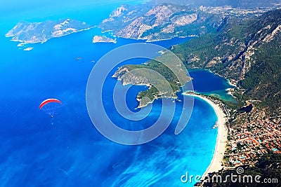 Paragliding flight over the blue lagoon of the Mediterranean Sea. Red dome of the parachute against the blue sea. Turkey. Oludeniz Stock Photo