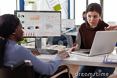 Paralyzed handicapped african american manager in wheelchair analyzing company statistics Stock Photo