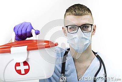 Paramedic in protective mask, glasses and blue latex gloves holds medical case Stock Photo