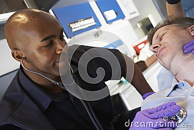 Paramedic using stethoscope on patient Stock Photo