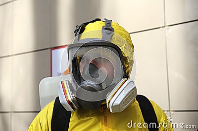 Paramedic wearing yellow protective costume and mask disinfecting coronavirus with the motorized backpack atomizer and sprayer Editorial Stock Photo