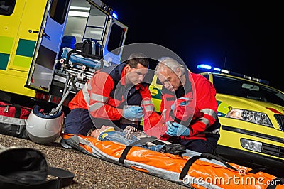 Paramedics giving firstaid to motorbike driver Stock Photo