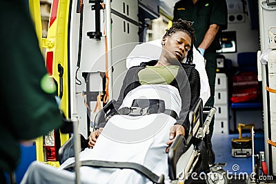 Paramedics moving a patient on a stretcher into an ambulance Stock Photo