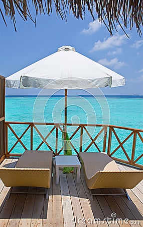 Parasol and chaise lounges on a terrace of water v Stock Photo