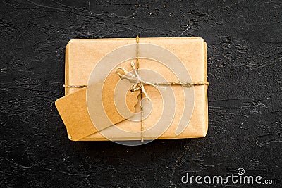 Parcel packaging box wrapped with craft paper with empty label mockup on black background top view copy space Stock Photo