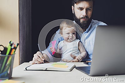 Parent with child studying remotely at homebased laptop. Distant education for people with babies.Man and toddler sitting at table Stock Photo