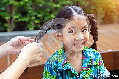 Parent make pigtail asian kid hair at park Stock Photo