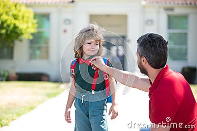 Parent and pupil of primary school. Teacher and cute schoolboy with backpack near school park. Stock Photo