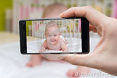 Parent is taking photo of a baby with smartphone Stock Photo